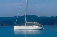 Sailing yacht Dufour 45E Performance 2009 on calm blue waters with scenic mountain backdrop.