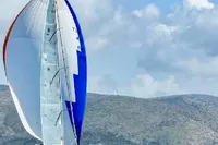 Sailing yacht Dufour 45E Performance 2009 with colorful spinnaker against mountainous backdrop.