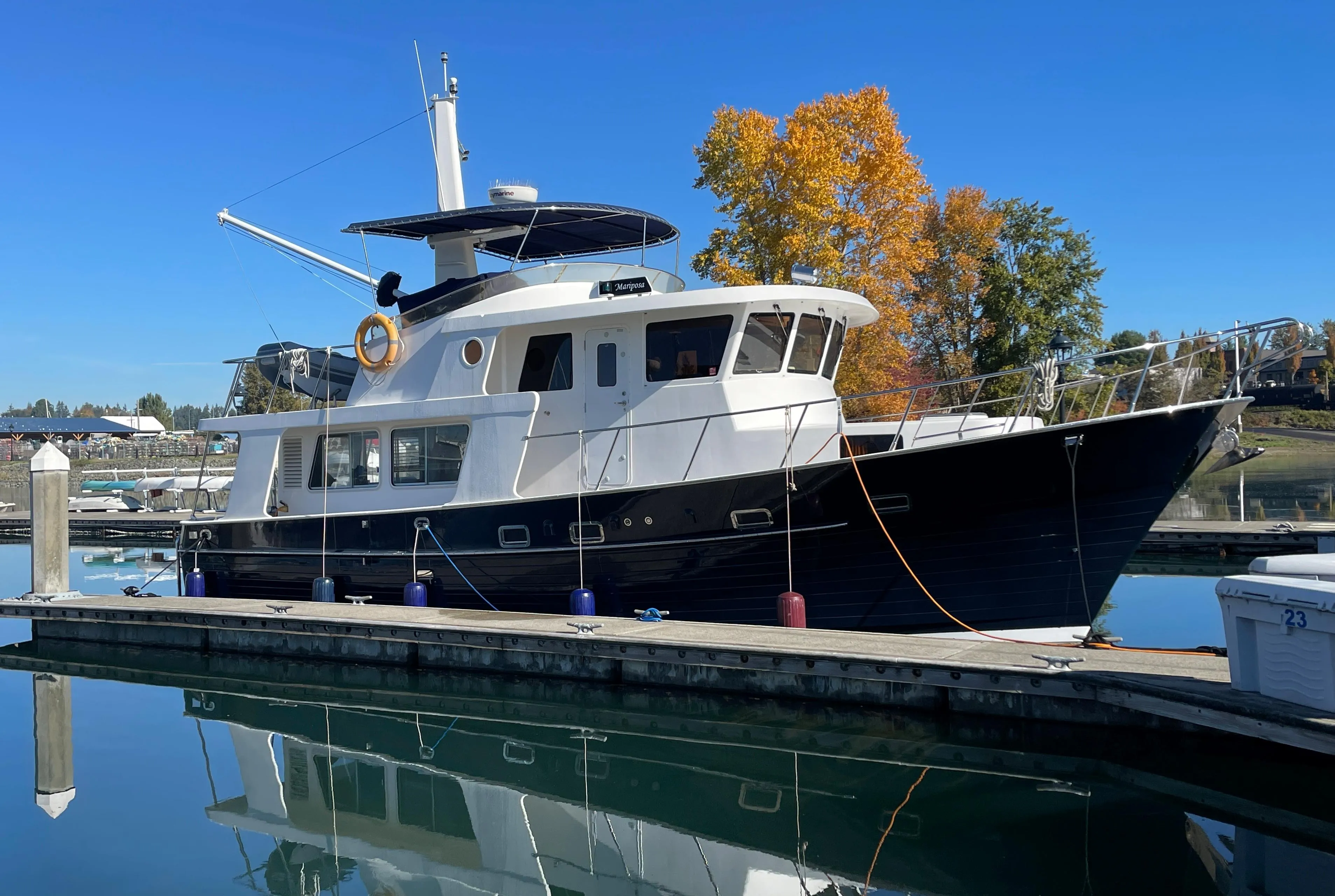 Integrity 45 yacht docked at marina, 2012 model, clear blue sky, autumn trees in background.