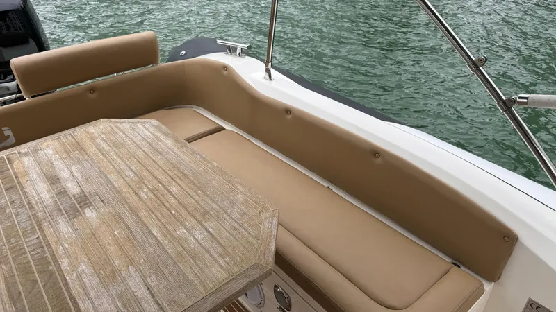 Hoko Yacht Photos Pics 2017 Nuova Jolly Princess boat interior with beige seating and wooden table by the water.