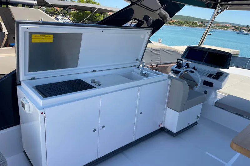  Yacht Photos Pics 2025 Ferretti Yachts 670 cockpit with helm, sink, and grill, overlooking marina.