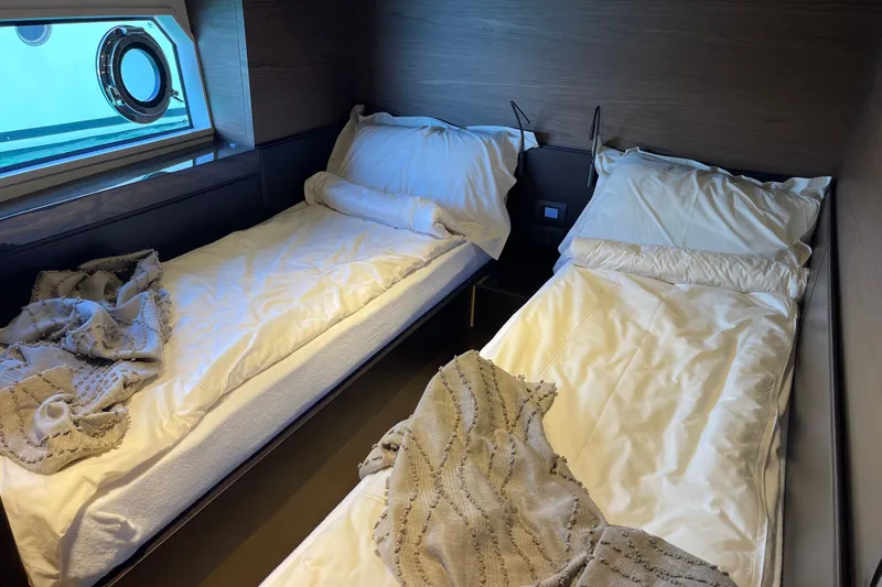  Yacht Photos Pics Twin cabin interior of 2025 Ferretti Yachts 670 with cozy bedding and porthole view.