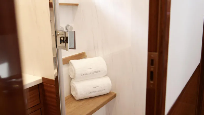 Lancia Aprea Yacht Photos Pics Luxurious bathroom with Lancia Aprea branded towels, wooden shelves, and modern fixtures.