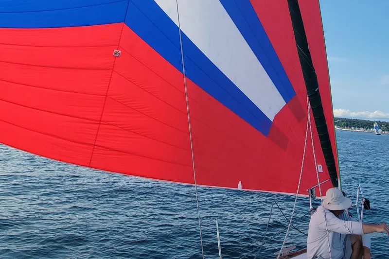 Phantom Yacht Photos Pics Sailing on a 2002 Beneteau 473 with vibrant red, blue, and white spinnaker.