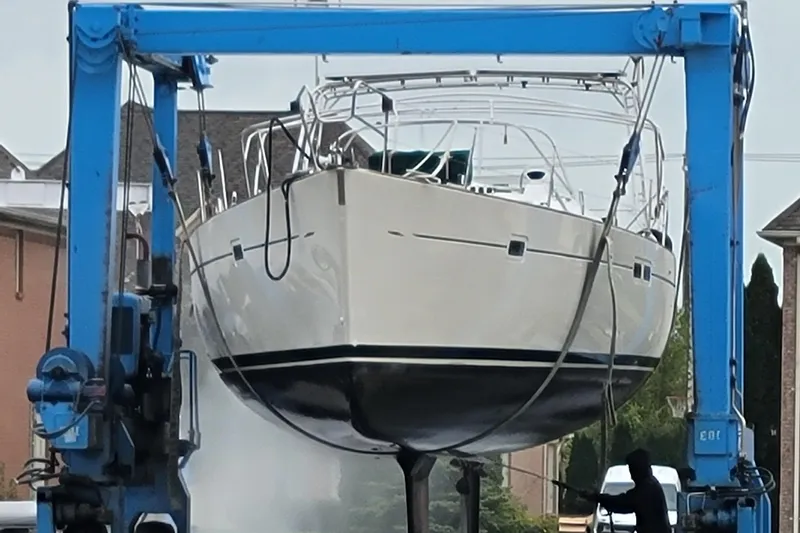 Phantom Yacht Photos Pics Beneteau 473 sailboat from 2002 being lifted by a blue crane for maintenance.