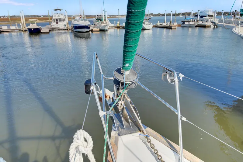 Phantom Yacht Photos Pics Bow of 2002 Beneteau 473 sailboat docked in a marina, surrounded by calm waters.