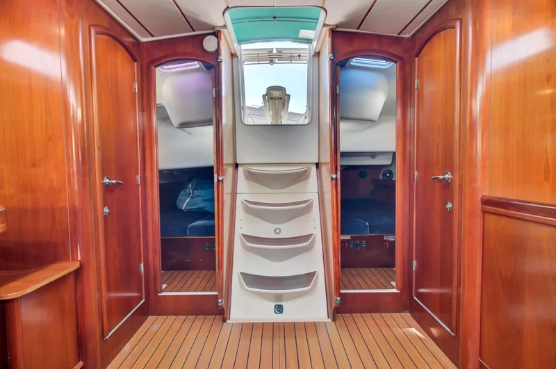 Phantom Yacht Photos Pics Interior of 2002 Beneteau 473 sailboat with wooden finish and central staircase.