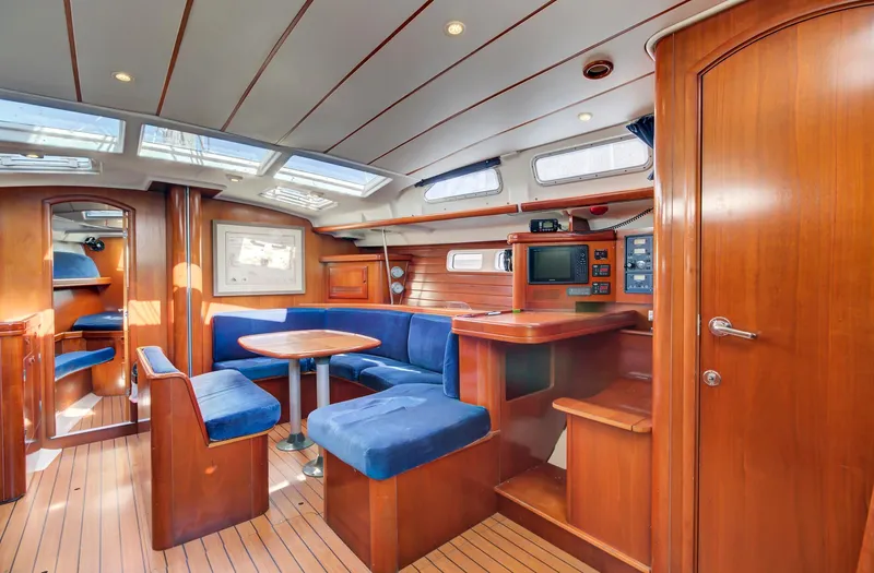 Phantom Yacht Photos Pics Interior of 2002 Beneteau 473 yacht with wood finish and blue seating.