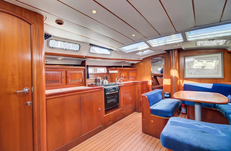 Phantom Yacht Photos Pics Interior of 2002 Beneteau 473 yacht with wood finish and blue seating.