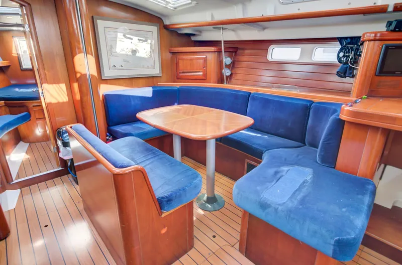 Phantom Yacht Photos Pics Interior of 2002 Beneteau 473 yacht with blue cushioned seating and wooden finishes.