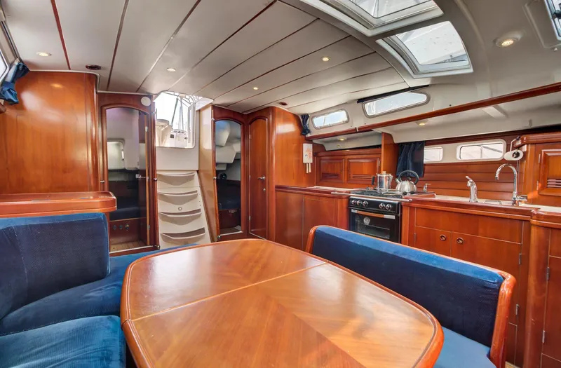 Phantom Yacht Photos Pics Interior of 2002 Beneteau 473 yacht with wooden dining area and kitchen.