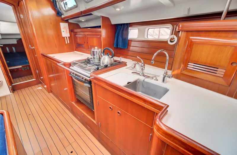 Phantom Yacht Photos Pics Interior of 2002 Beneteau 473 yacht kitchen with wood cabinetry and modern appliances.