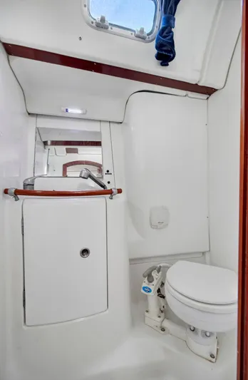 Phantom Yacht Photos Pics 2002 Beneteau 473 yacht bathroom with compact toilet and sink, featuring white and wood accents.