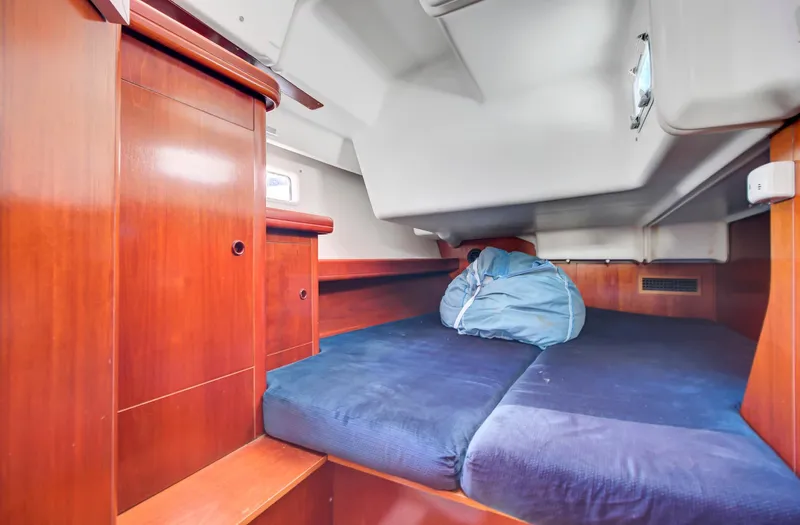 Phantom Yacht Photos Pics Cozy cabin interior of 2002 Beneteau 473 sailboat with wooden finish and blue bedding.