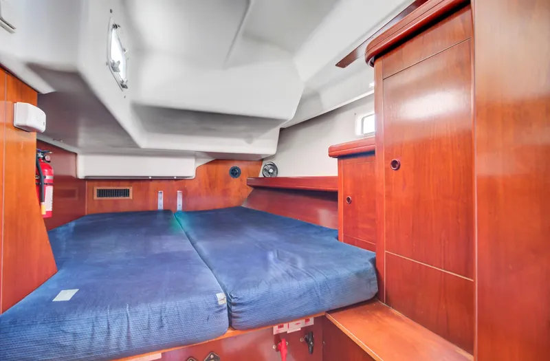 Phantom Yacht Photos Pics 2002 Beneteau 473 yacht cabin with blue bedding and wooden interior.