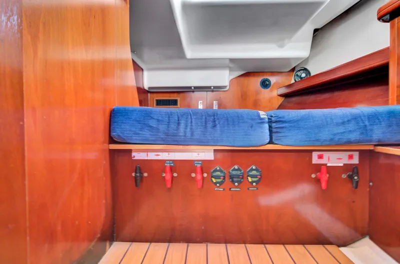 Phantom Yacht Photos Pics Interior of 2002 Beneteau 473 sailboat with blue cushions and wooden paneling.