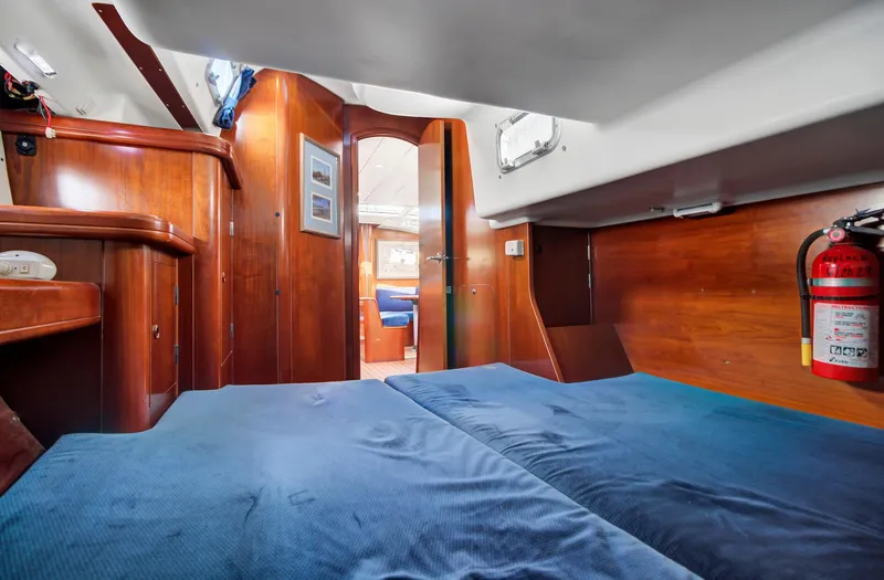 Phantom Yacht Photos Pics Interior cabin of 2002 Beneteau 473 yacht with wooden finish and blue bedding.
