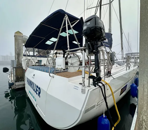 Painkiller Yacht Photos Pics 2020 Bavaria C50 sailboat docked, featuring a blue canopy and outboard motor.