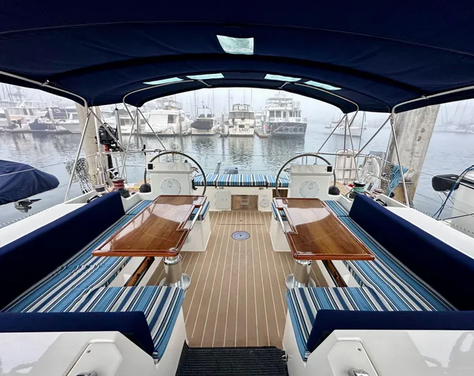 Painkiller Yacht Photos Pics Luxurious 2020 Bavaria C50 yacht interior with elegant seating and wooden tables in a marina.