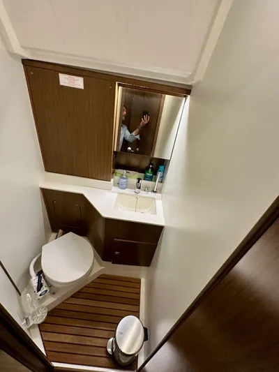 Painkiller Yacht Photos Pics 2020 Bavaria C50 yacht bathroom with toilet, sink, mirror, and wooden flooring.