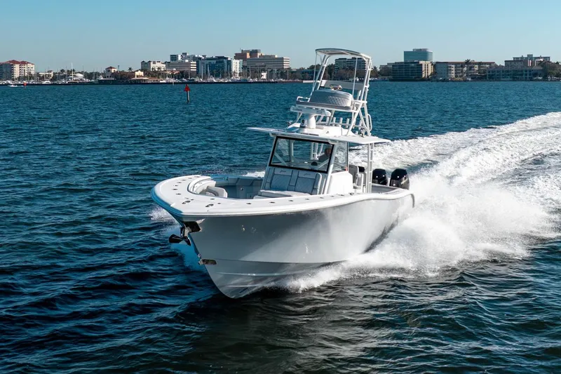  Yacht Photos Pics 2023 Yellowfin 42 Offshore boat cruising on open water near city skyline.