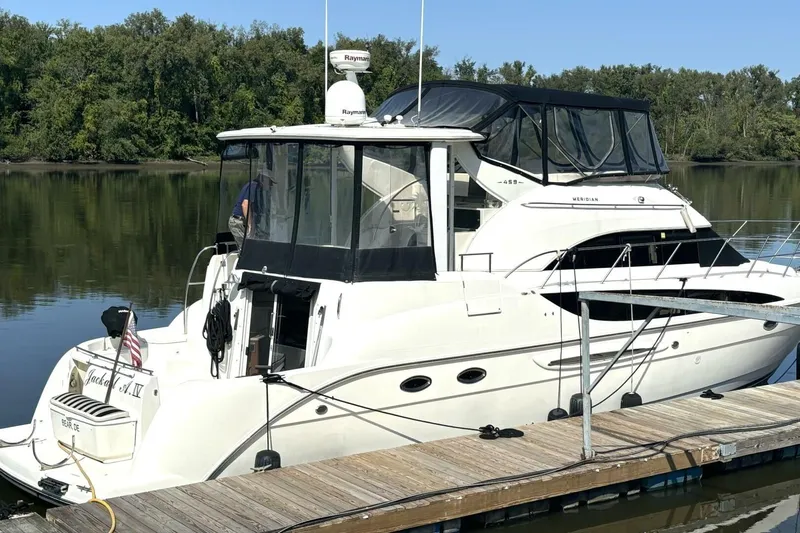  Yacht Photos Pics 2004 Meridian 459 Cockpit Motoryacht docked on a calm river with lush greenery.