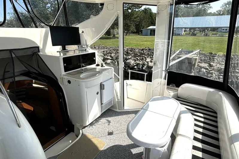  Yacht Photos Pics 2004 Meridian 459 Cockpit Motoryacht interior with seating, sink, and TV, overlooking grassy landscape.