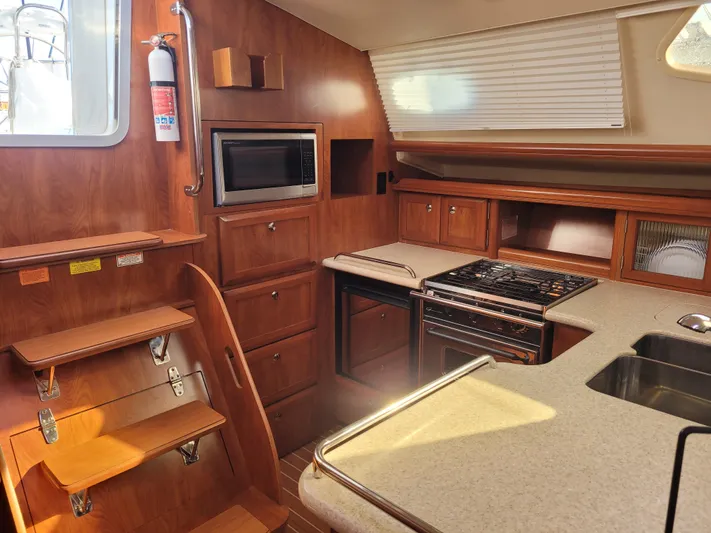 Caribbean Breeze Yacht Photos Pics Interior of 2010 Hunter 45 Deck Salon yacht kitchen with wood cabinetry and modern appliances.