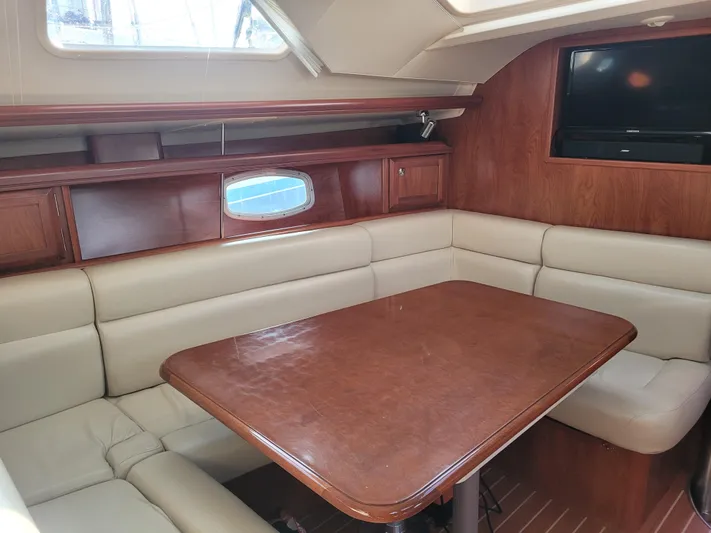 Caribbean Breeze Yacht Photos Pics Interior of 2010 Hunter 45 Deck Salon with wood table and beige seating.
