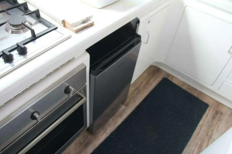 Chasing The Dream Yacht Photos Pics Compact kitchen area in a 1995 Voyage Yachts Mayotte, featuring stove and fridge.