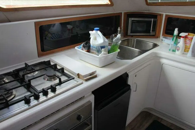 Chasing The Dream Yacht Photos Pics 1995 Voyage Yachts Mayotte kitchen with stove, sink, and cleaning supplies.