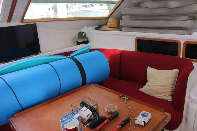 Chasing The Dream Yacht Photos Pics Interior of 1995 Voyage Yachts Mayotte with red seating, blue mat, and various items on table.