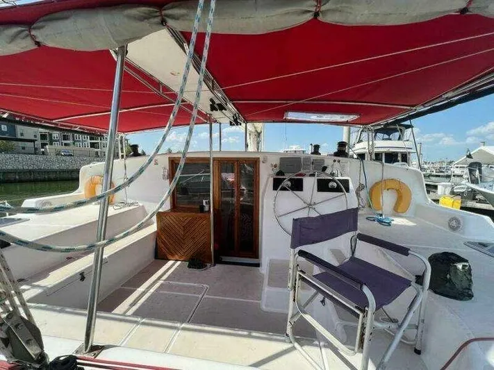 Chasing The Dream Yacht Photos Pics 1995 Voyage Yachts Mayotte catamaran with red canopy, spacious deck, and marina view.