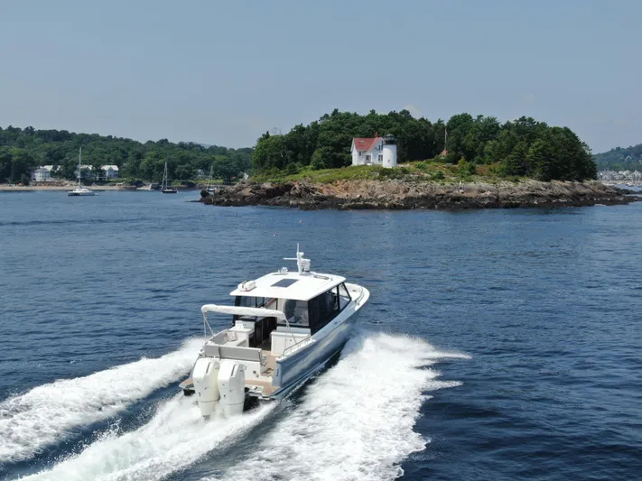 Artemis Yacht Photos Pics 2023 MJM 4 boat cruising near a scenic island with a lighthouse.