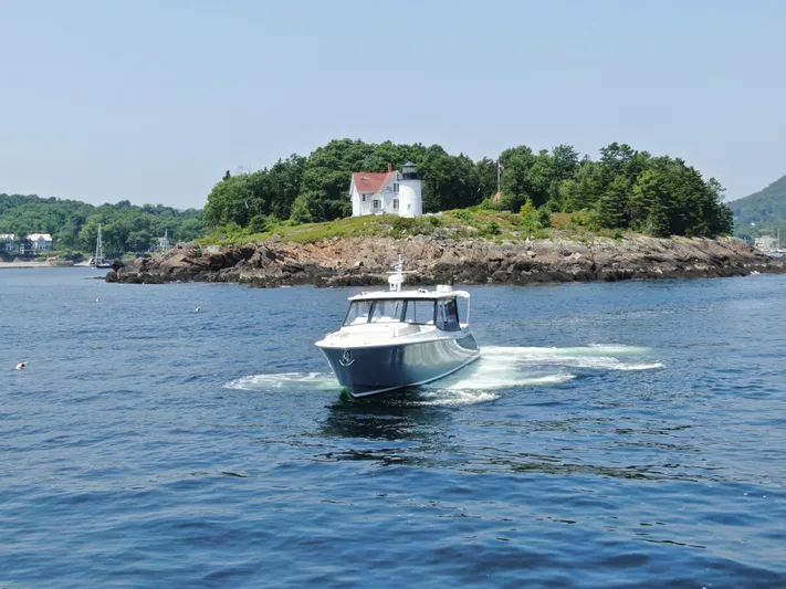 Artemis Yacht Photos Pics 2023 MJM 4 boat cruising near a scenic island with a lighthouse.
