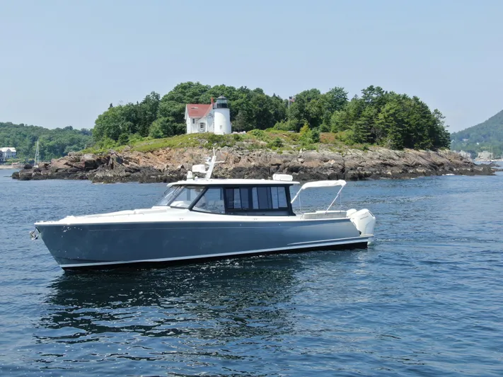 Artemis Yacht Photos Pics 2023 MJM 4 boat cruising near a rocky island with a lighthouse.