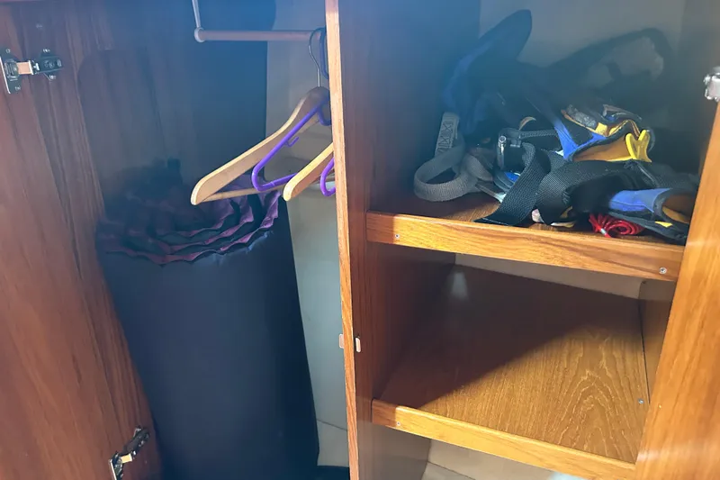 Summer Solace Yacht Photos Pics Wooden closet interior on Jeanneau Sun Odyssey 40 yacht, featuring hangers and storage shelves.