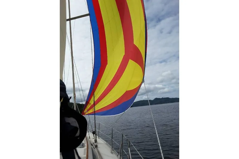 Summer Solace Yacht Photos Pics Jeanneau Sun Odyssey 40 sailing with colorful spinnaker on a cloudy day, 2000 model.