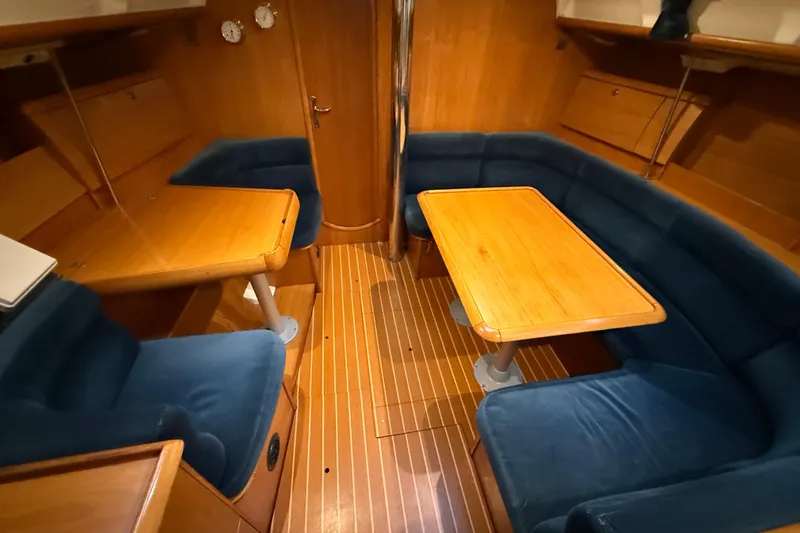 Summer Solace Yacht Photos Pics Interior of 2000 Jeanneau Sun Odyssey 40 yacht with wooden tables and blue seating.