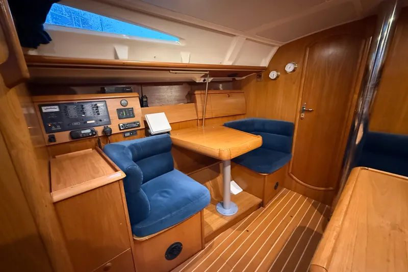 Summer Solace Yacht Photos Pics Cozy interior of 2000 Jeanneau Sun Odyssey 40 sailboat with wooden furnishings and blue seating.