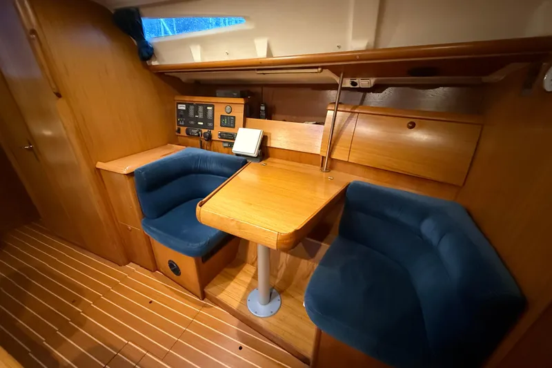 Summer Solace Yacht Photos Pics Interior of 2000 Jeanneau Sun Odyssey 40 sailboat with wooden table and blue seating.