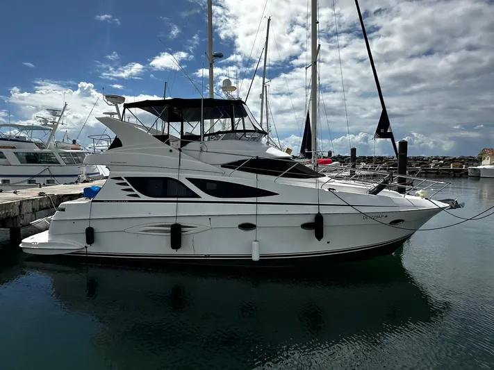  Yacht Photos Pics 2006 Silverton 43 Sport Bridge yacht docked in a marina under a partly cloudy sky.