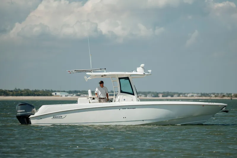  Yacht Photos Pics 2013 Boston Whaler 320 Outrage boat cruising on calm waters under a cloudy sky.