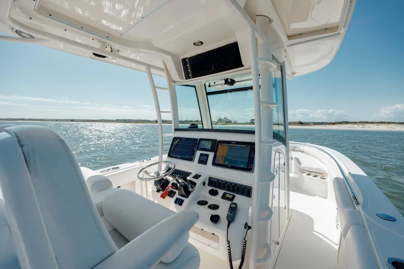  Yacht Photos Pics 2013 Boston Whaler 320 Outrage boat interior with navigation controls, on calm water.