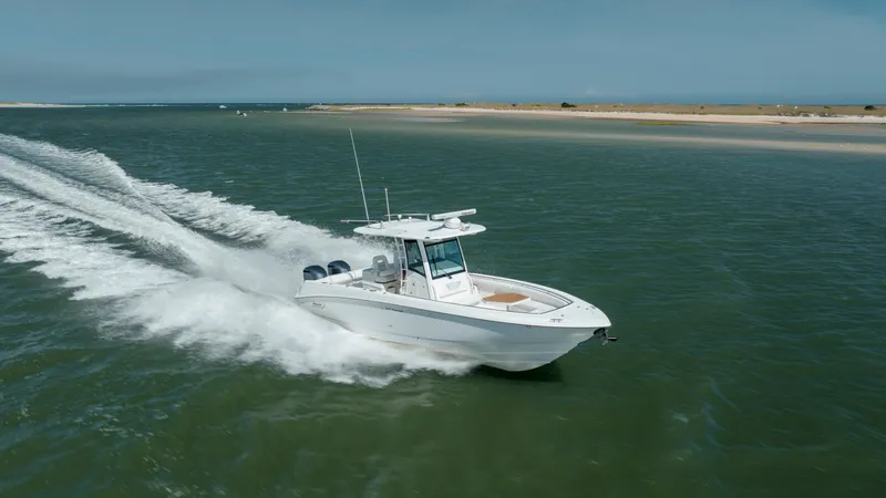  Yacht Photos Pics 2013 Boston Whaler 320 Outrage cruising on open water near a sandy shoreline.