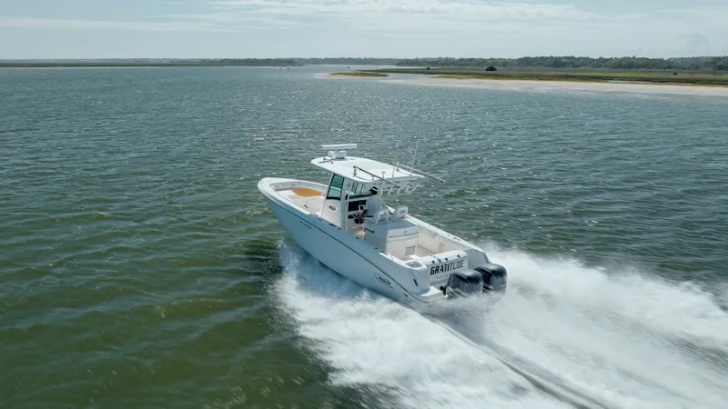  Yacht Photos Pics 2013 Boston Whaler 320 Outrage cruising on open water near a coastline.