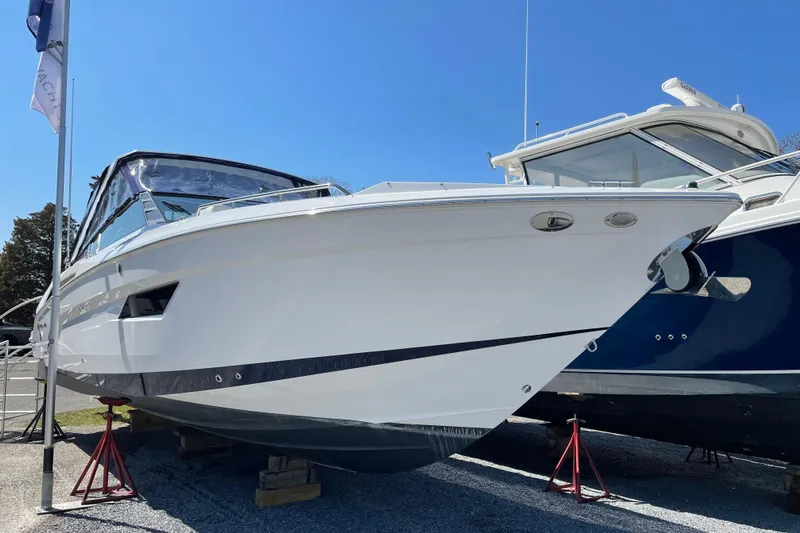 Yacht Photos Pics 2021 Cruisers Yachts 338 Outboard, white hull, displayed on stands, clear blue sky background.