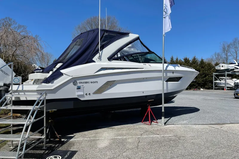  Yacht Photos Pics 2021 Cruisers Yachts 338 Outboard on display, parked outdoors under clear blue sky.