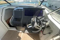 Helm of 2021 Nimbus T11 boat with dual screens and steering wheel, docked at marina.