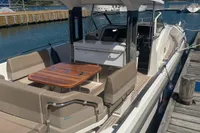 2021 Nimbus T11 boat docked, featuring spacious seating and a wooden table under a clear sky.